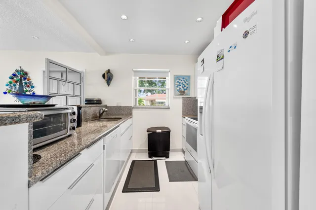 a kitchen with granite countertop a refrigerator stove and sink