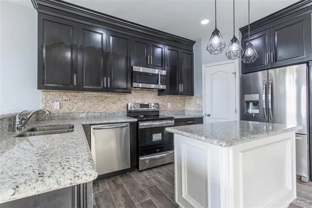 a kitchen with stainless steel appliances granite countertop wooden cabinets a stove top oven a sink and dishwasher