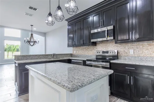 a kitchen with stainless steel appliances granite countertop wooden cabinets a stove top oven a sink and dishwasher