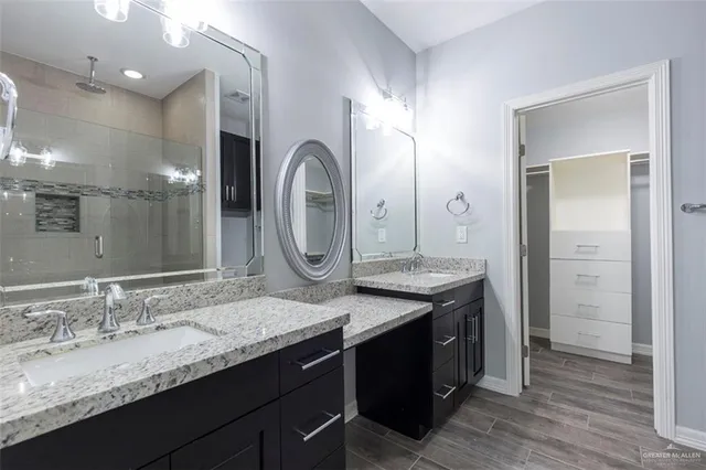 a bathroom with a granite countertop double vanity sink and a mirror