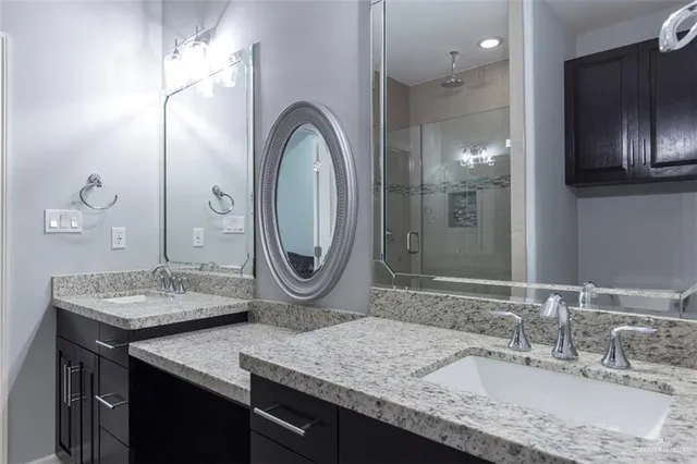 a bathroom with a granite countertop sink a mirror and shower