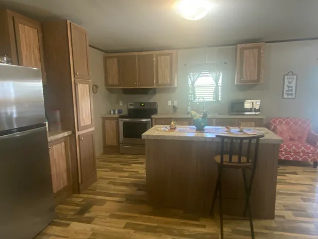 a kitchen with stainless steel appliances granite countertop a refrigerator a sink a stove a dining table and chairs