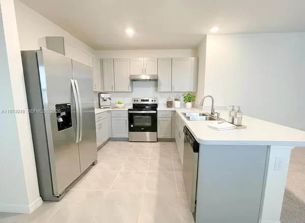 a kitchen with stainless steel appliances a sink a stove a refrigerator cabinets and a window