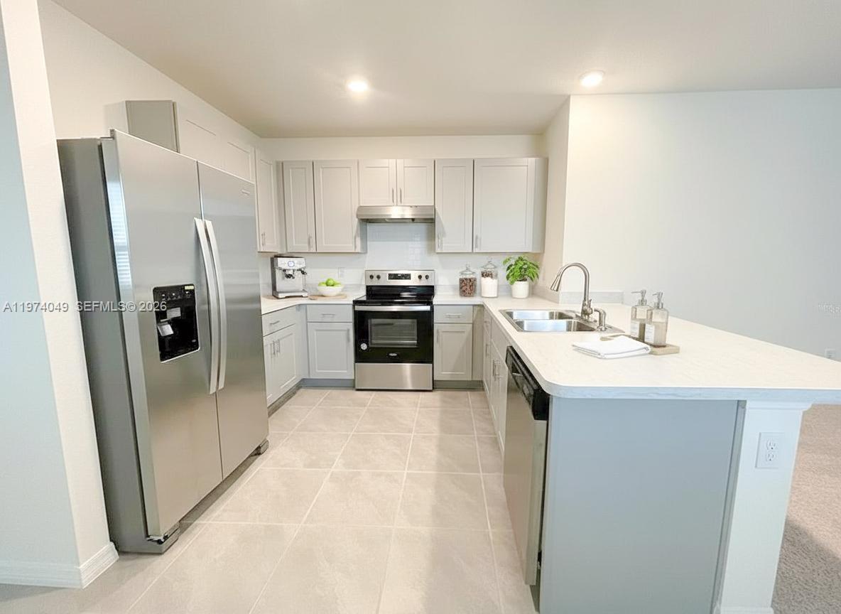 1556 Gladewater Road, Unit 1556 Kissimmee, FL 34744 - Photo 2 of 26 a kitchen with stainless steel appliances a sink a stove a refrigerator cabinets and a window