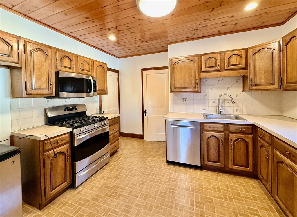 15 Belvoir Road, Unit 2 Milton, MA 02186 - Photo 6 of 13 a kitchen with stainless steel appliances granite countertop a stove top oven a sink dishwasher and white cabinets with wooden floor