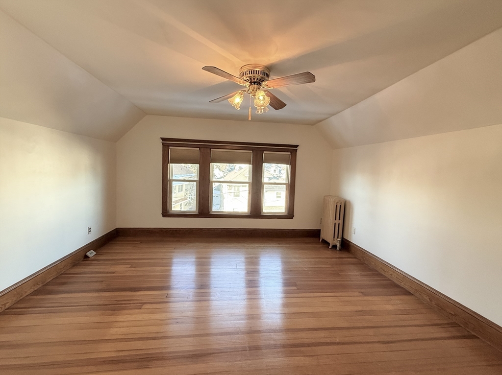 15 Belvoir Road, Unit 2 Milton, MA 02186 - Photo 9 of 13 an empty room with wooden floor chandelier fan and windows