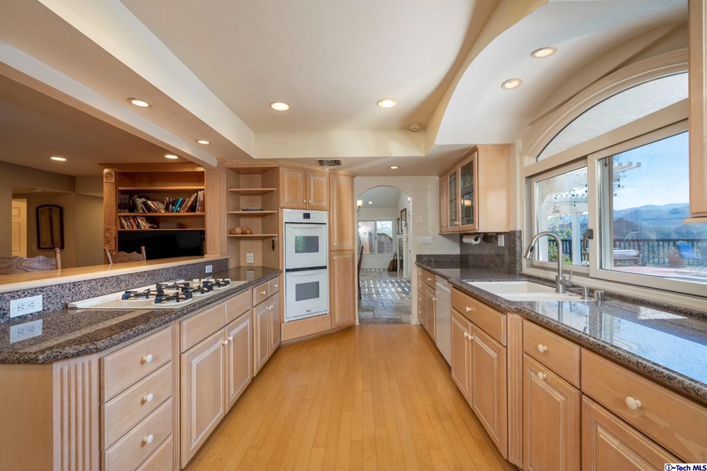 24718 Sagecrest Circle Newhall, CA 91381 - Photo 23 of 36 a large kitchen with stainless steel appliances a large counter top a stove a sink and a refrigerator