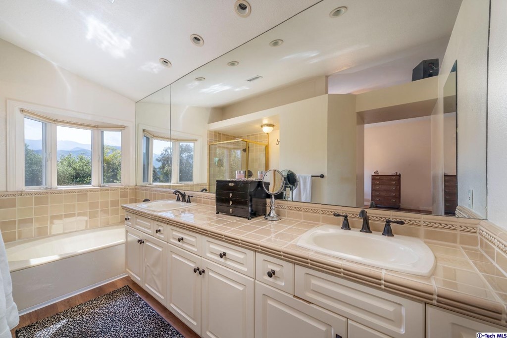 24718 Sagecrest Circle Newhall, CA 91381 - Photo 32 of 36 a bathroom with double vanity sinks a large mirror and a bathtub
