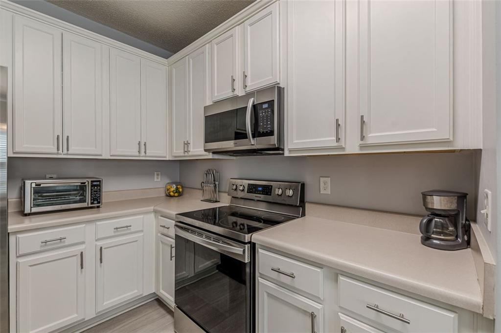 7640 Rutgers Circle Fairburn, GA 30213 - Photo 22 of 49 a kitchen with granite countertop white cabinets and a stove top oven