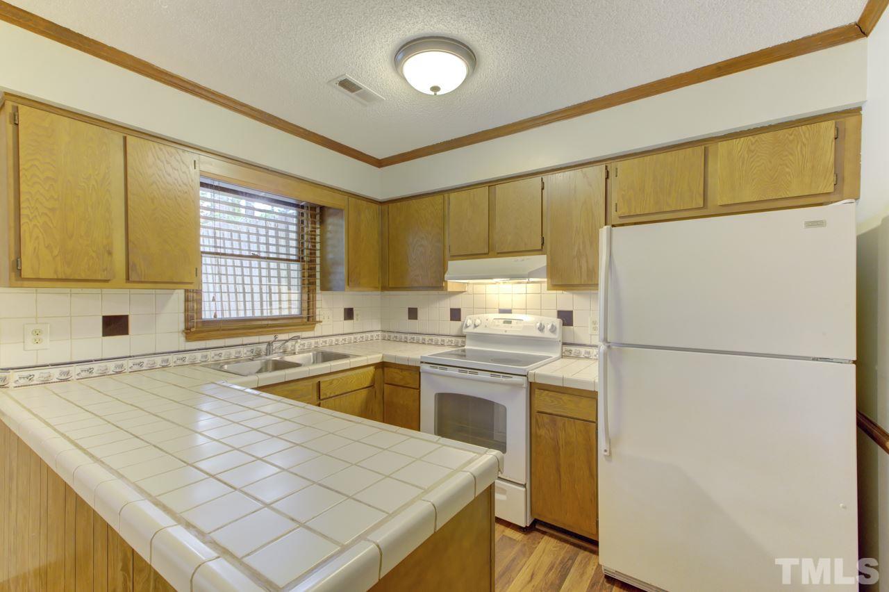 5505 Hamstead Crossing Raleigh, NC 27612 - Photo 11 of 25 a kitchen with a refrigerator a stove a sink and cabinets