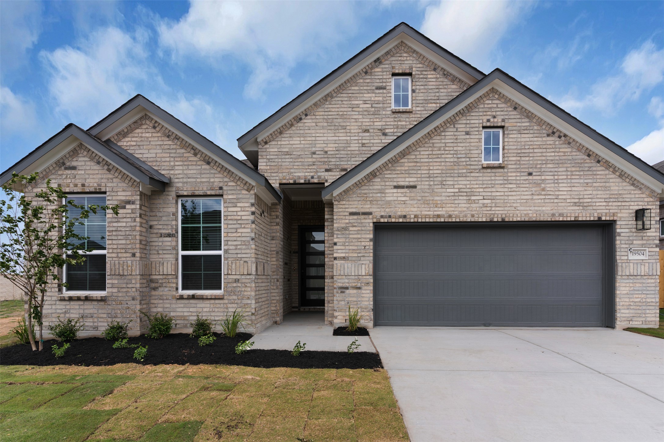 19504 Domino Champ Road Pflugerville, TX 78660 - Photo 1 of 24 View of front facade featuring driveway, brick siding, a front lawn, and a garage