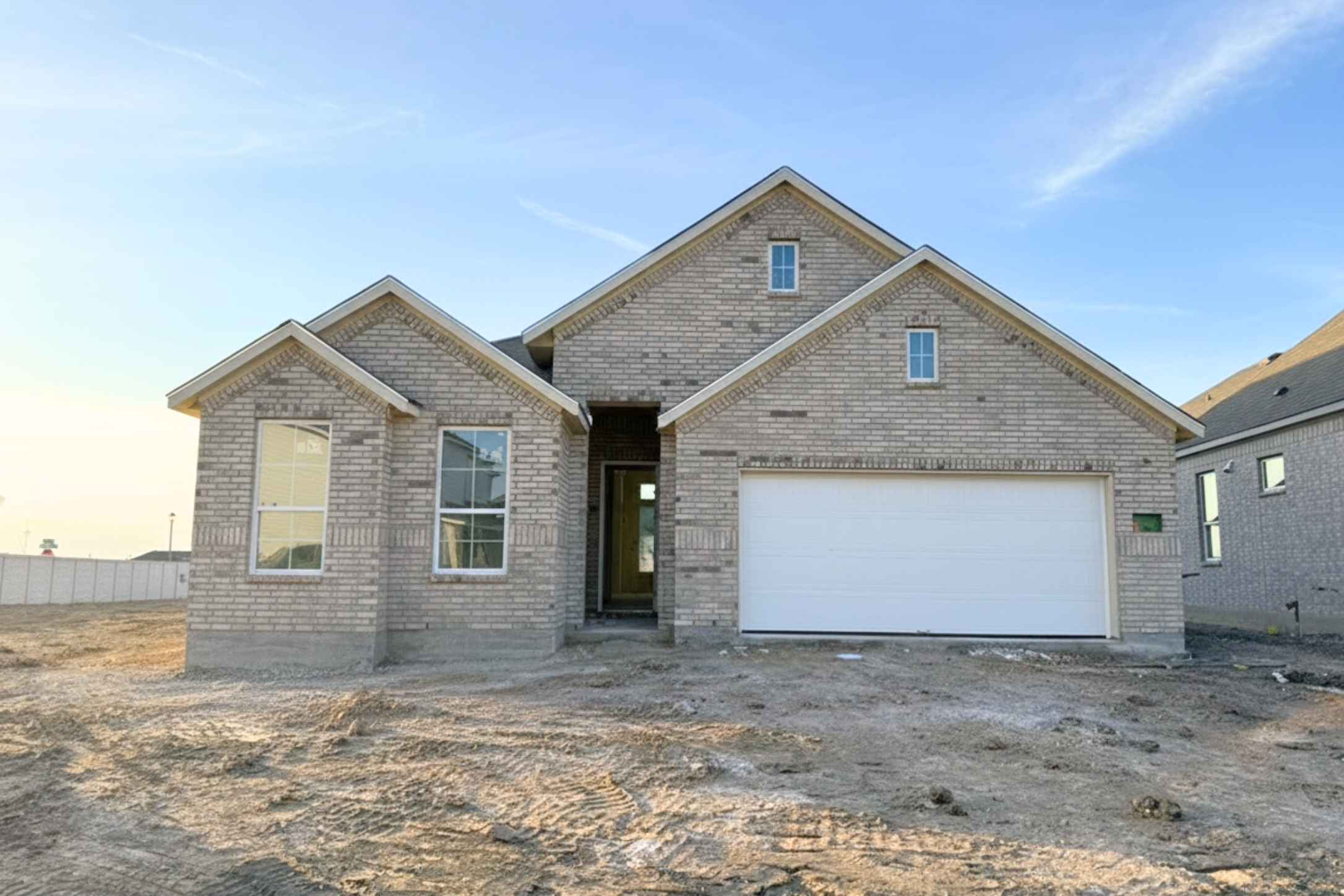 View of front of house with dirt driveway, brick siding, and a garage