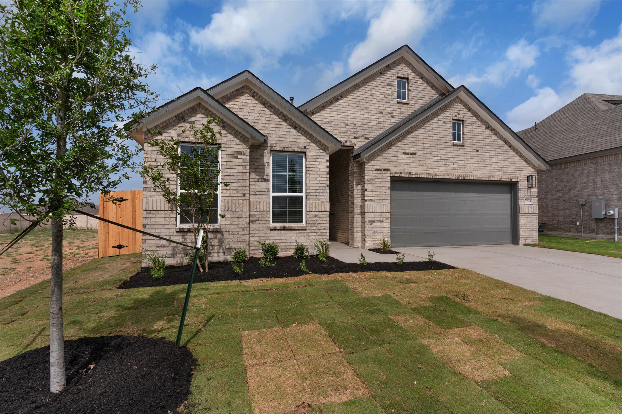 19504 Domino Champ Road Pflugerville, TX 78660 - Photo 2 of 24 View of front facade with brick siding, driveway, a front lawn, and a garage