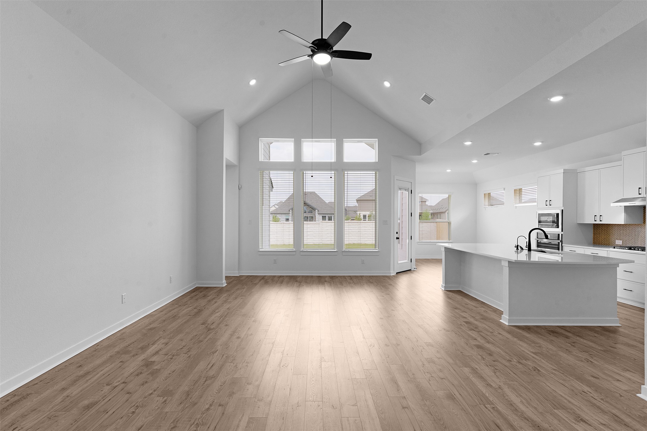 19504 Domino Champ Road Pflugerville, TX 78660 - Photo 8 of 24 Unfurnished living room with a high ceiling, ceiling fan, light wood-type flooring, plenty of natural light, and recessed lighting
