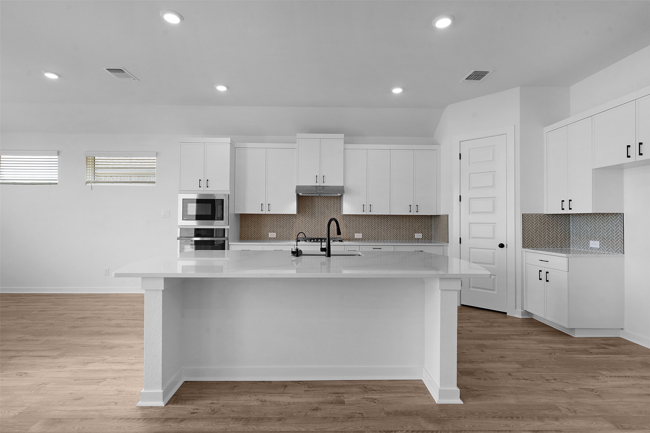 19504 Domino Champ Road Pflugerville, TX 78660 - Photo 10 of 24 Kitchen with white cabinets, light stone countertops, backsplash, light wood finished floors, and recessed lighting