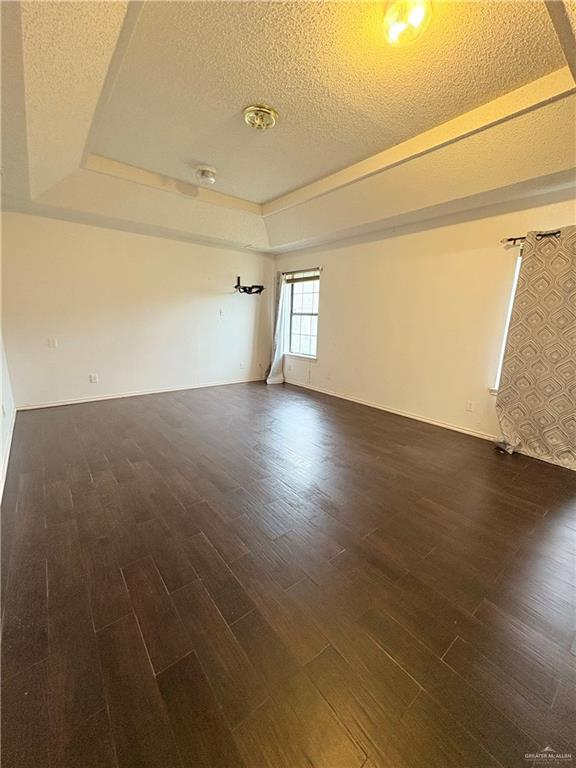 2218 Lawndale Road Mission, TX 78572 - Photo 14 of 24 Spare room with baseboards, wood finished floors, a tray ceiling, and a textured ceiling