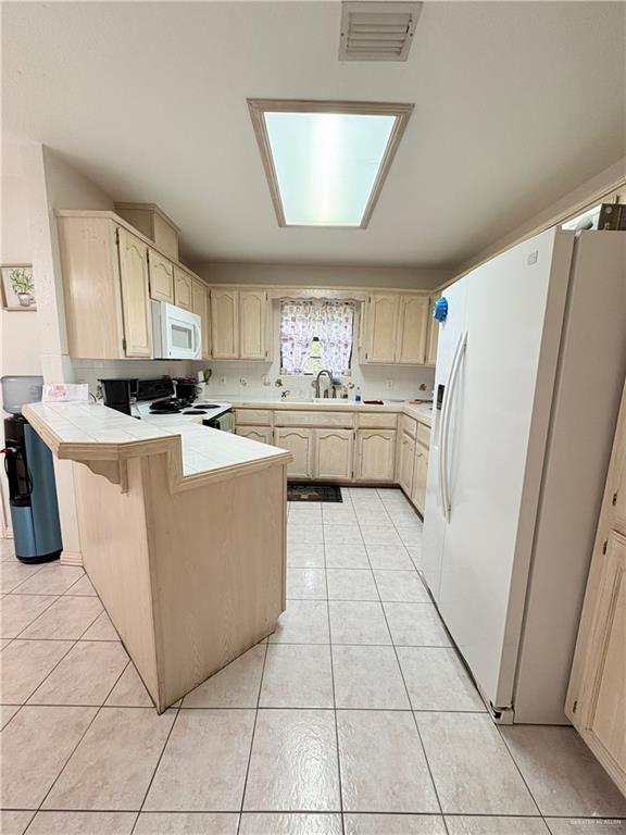2218 Lawndale Road Mission, TX 78572 - Photo 6 of 24 Kitchen featuring tile counters, visible vents, a sink, white appliances, and a peninsula