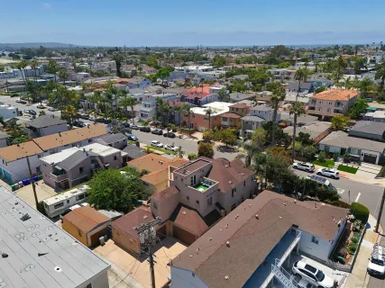 an aerial view of a city with lots of residential buildings ocean and mountain view in back
