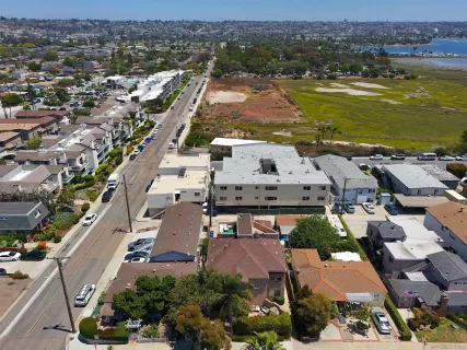 an aerial view of a city with lots of residential buildings and ocean view in back