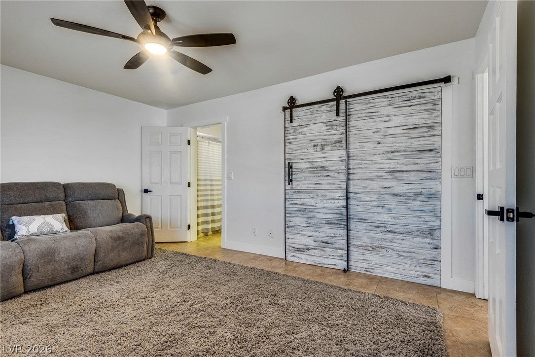 524 Swallow Cove Boulder City, NV 89005 - Photo 30 of 58 A relaxed living space with a ceiling fan, plush carpet, and stylish barn doors, offering comfort and charm.