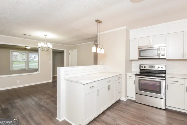 a kitchen with stainless steel appliances granite countertop a stove a sink and a microwave