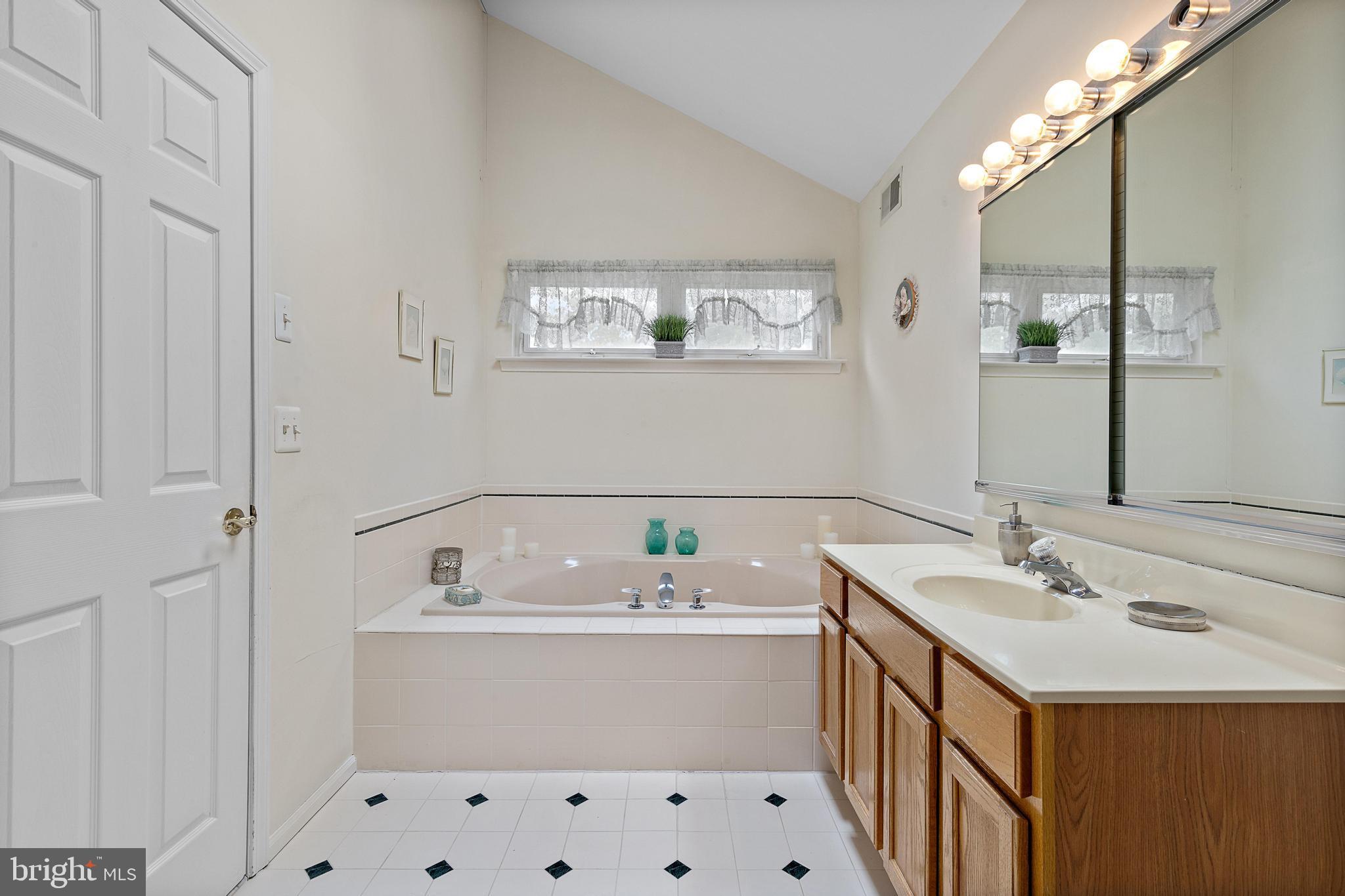 249 Topside Road Manahawkin, NJ 08050 - Photo 40 of 49 a bathroom with a bathtub a sink and a mirror
