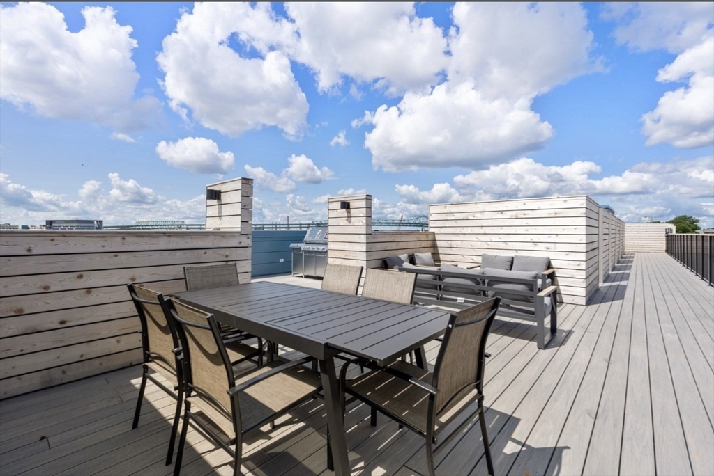 301 Border Street, Unit 610 Boston, MA 02128 - Photo 11 of 17 a view of a roof deck with dining table and chairs with wooden floor