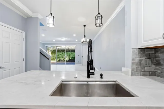 a kitchen with a sink a counter top space and a chandelier