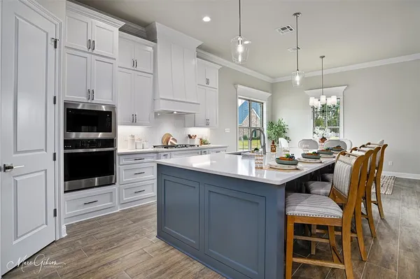 a kitchen with stainless steel appliances kitchen island granite countertop a table chairs and a refrigerator