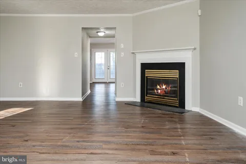 a view of an empty room with wooden floor and a fireplace