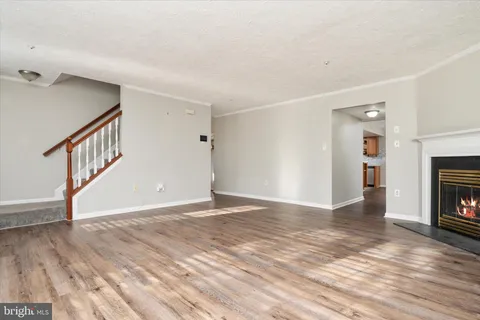 a view of an empty room with wooden floor fireplace and a window