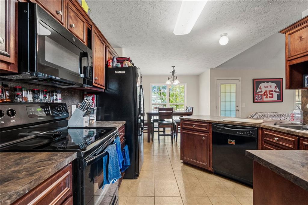 2 Bon Acre Road Fort Mitchell, AL 36856 - Photo 6 of 15 Kitchen featuring black appliances, dark countertops, light tile patterned floors, a textured ceiling, and a peninsula