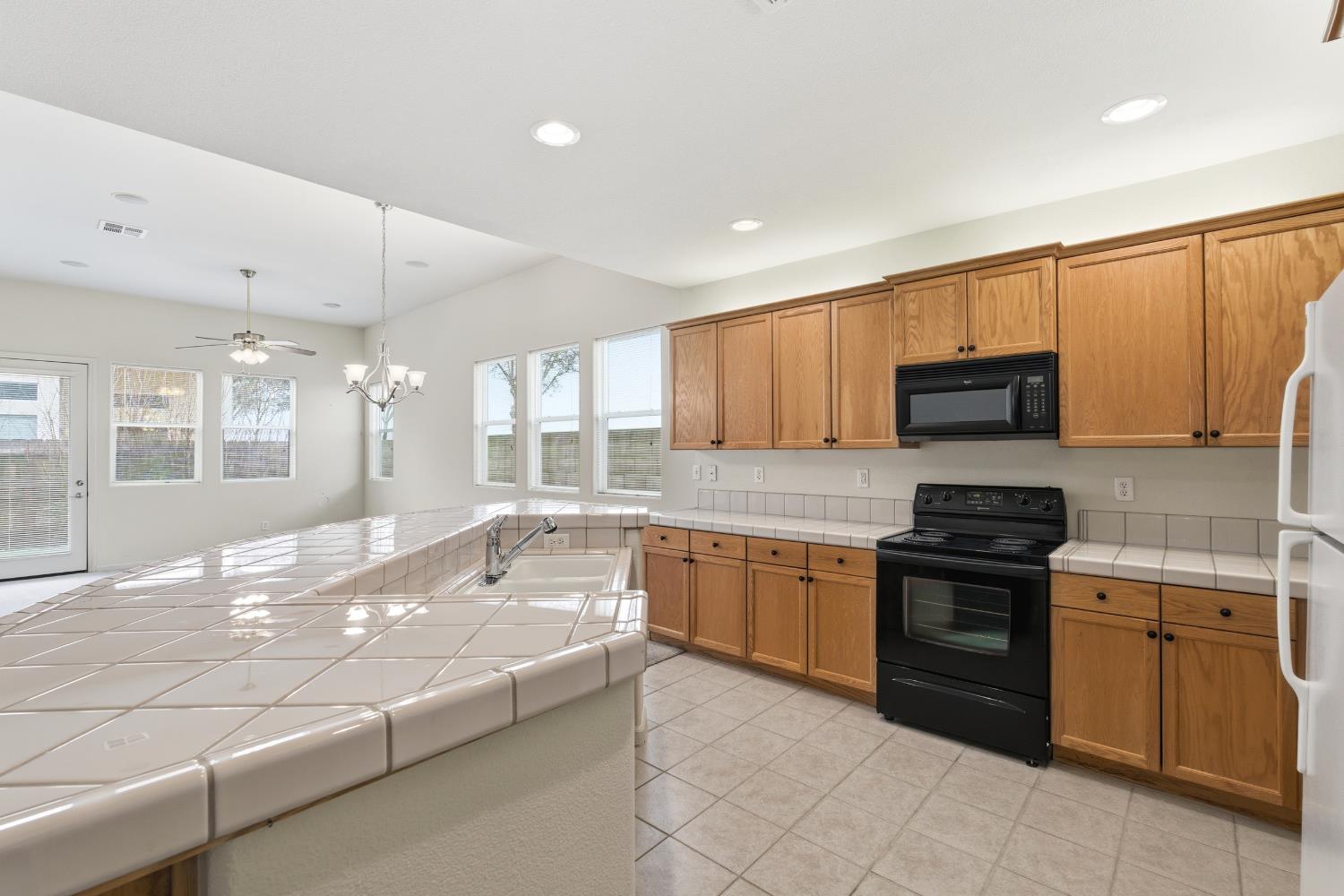 2450 Como Corte Chowchilla, CA 93610 - Photo 13 of 42 a large kitchen with granite countertop a stove top oven a sink a counter space and cabinets
