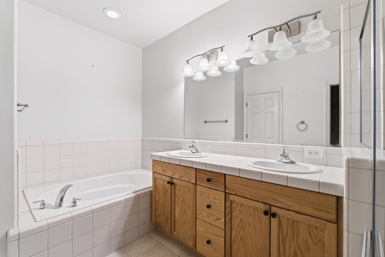 2450 Como Corte Chowchilla, CA 93610 - Photo 20 of 42 a bathroom with a granite countertop bathtub a sink and a mirror