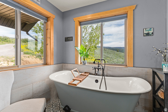2013 North River View Road Huntsville, UT 84317 - Photo 20 of 53 Bathroom featuring tile walls, a soaking tub, a wainscoted wall, and healthy amount of natural light