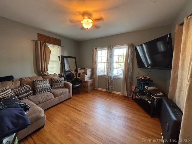 a living room with furniture a flat screen tv and wooden floor
