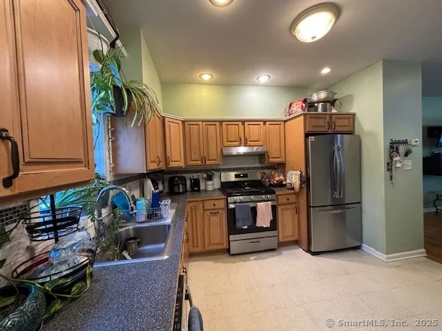 a kitchen with stainless steel appliances granite countertop a refrigerator and a stove