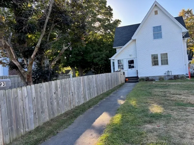 a view of backyard with wooden fence and large trees
