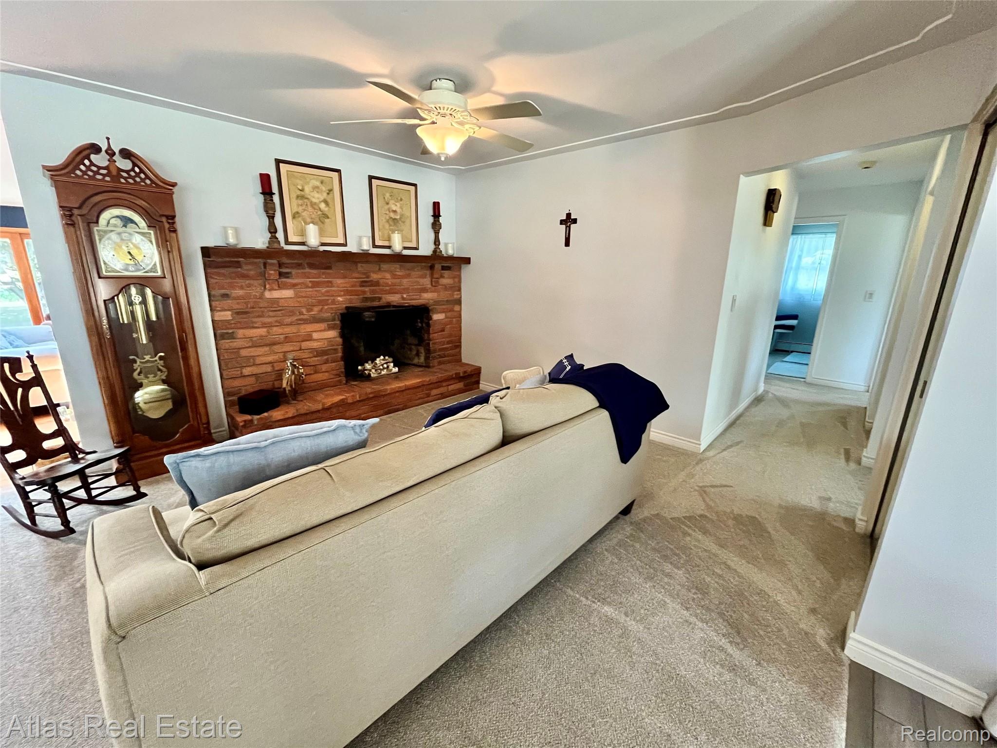 12026 Coolidge Road Goodrich, MI 48438 - Photo 30 of 56 Brick fireplace with a wood mantel, ceiling fan with integrated lighting, and neutral-toned wall-to-wall carpeting