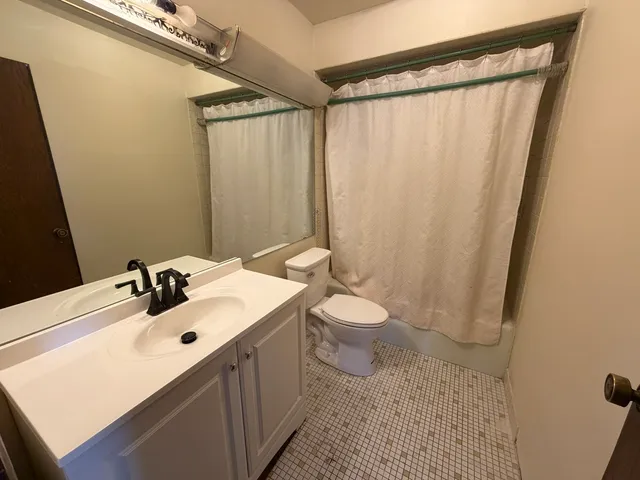 a bathroom with a sink a toilet a mirror and shower curtain