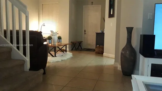 a living room with furniture a flat screen tv and a refrigerator