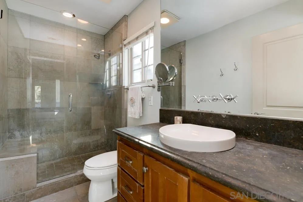 445 E Avenue Coronado, CA 92118 - Photo 18 of 25 a bathroom with a granite countertop sink toilet a mirror and shower