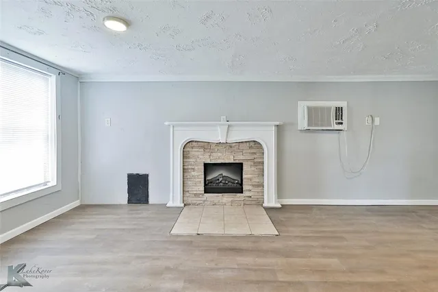 an empty room with windows and fireplace