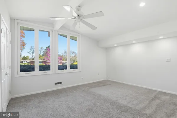 an empty room with windows and fan