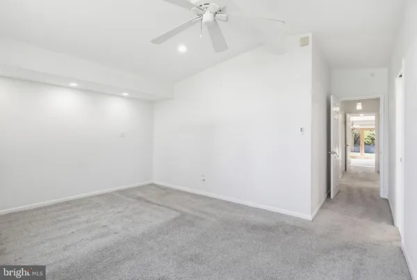 an empty room with a ceiling fan and carpet