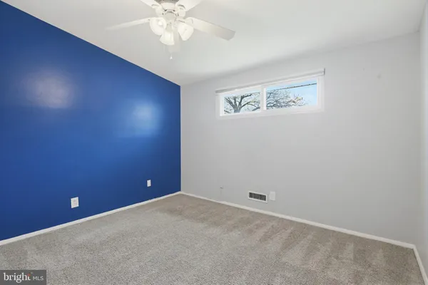 an empty room with a fan & a window