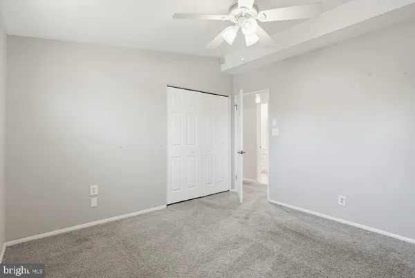 an empty room with a chandelier fan and closet area