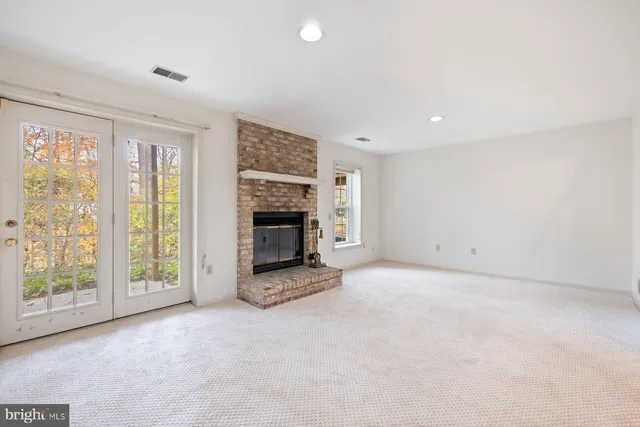 an empty room with windows and fireplace