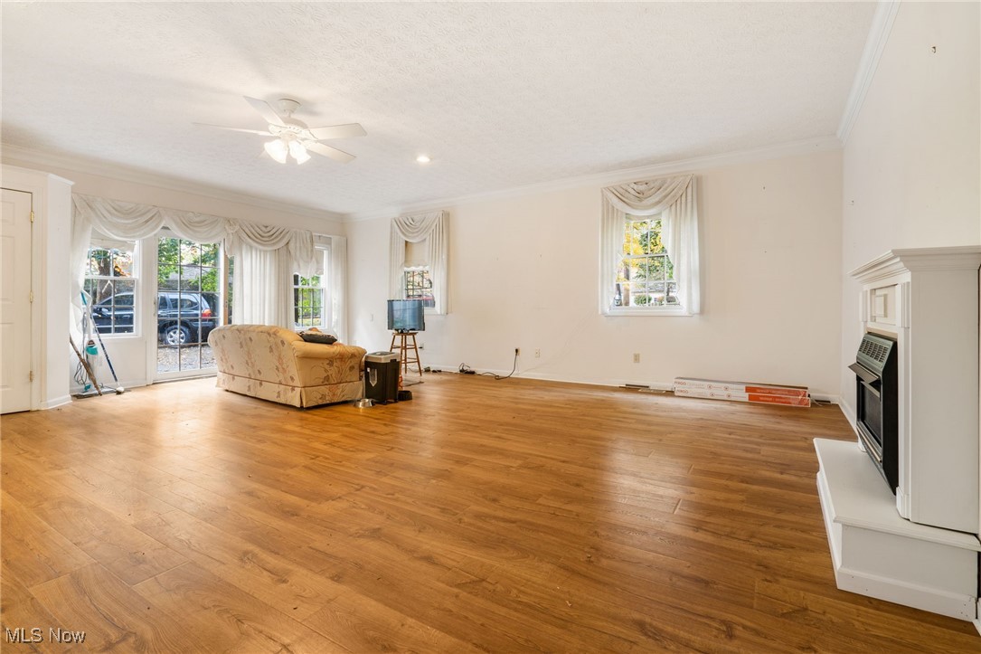 4057 Etter Road Mogadore, OH 44260 - Photo 20 of 41 Unfurnished living room with crown molding, a healthy amount of sunlight, light wood-type flooring, and ceiling fan