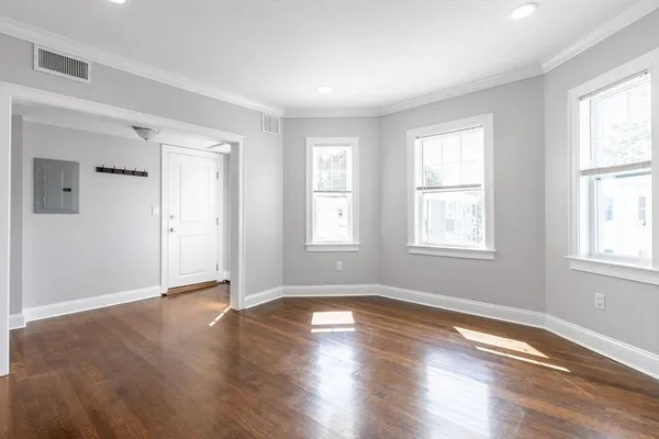a view of an empty room with wooden floor and a window